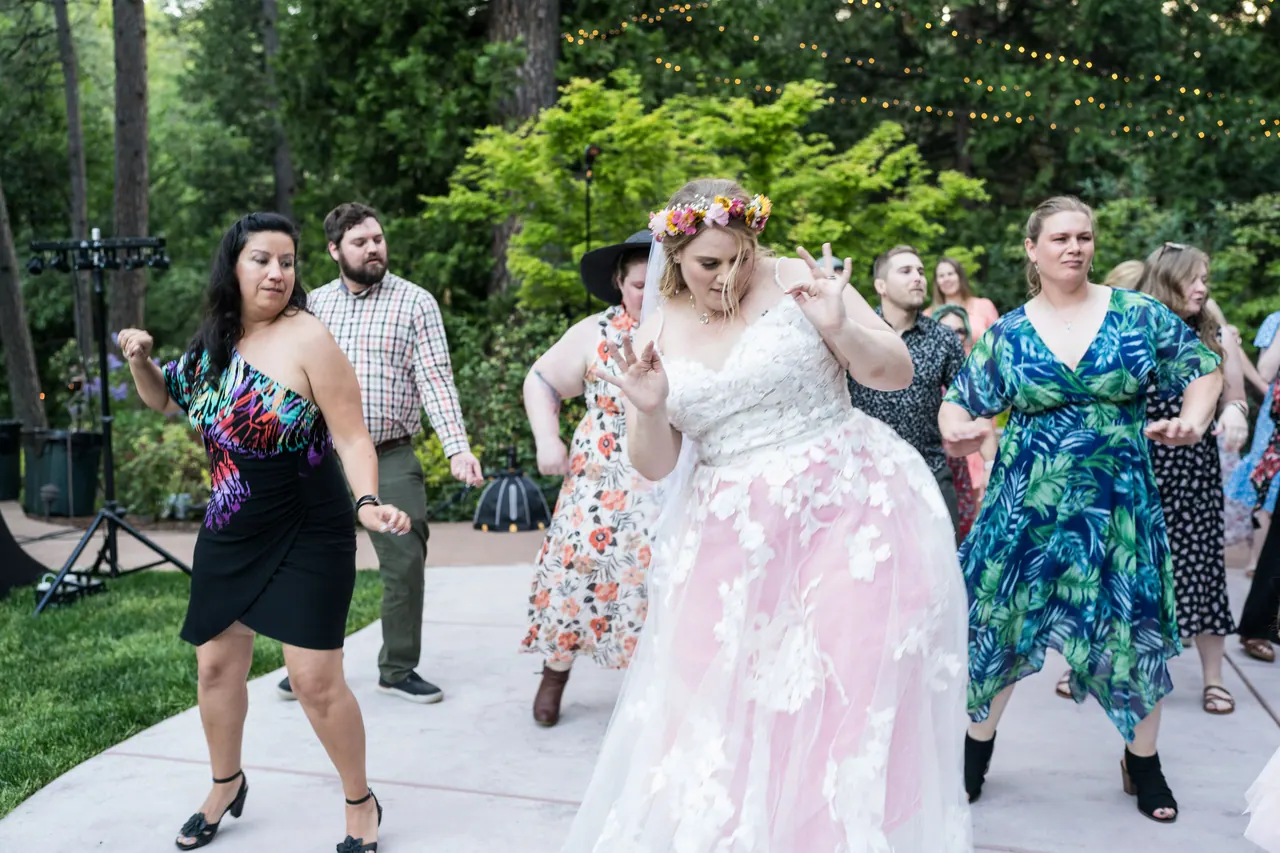 Abney leads a group dance on the patio with her wedding guests dancing along behind her