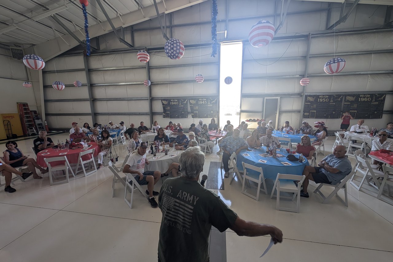 A host in a U.S. Army shirt welcoming the full hangar from the mic