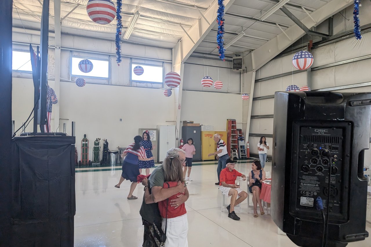 Two guests sharing a hug beside the speaker in the hangar