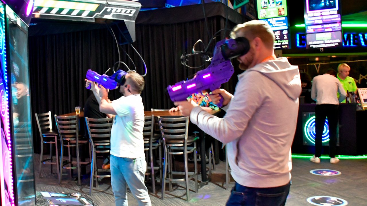 Two AMUG guests in VR headsets aiming purple blasters