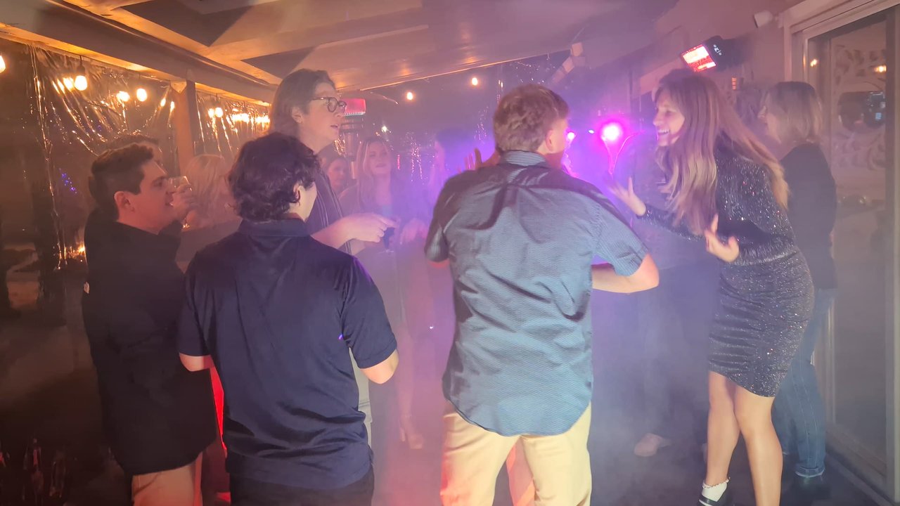 A guest in a sparkly dress laughing on the fog filled patio dance floor