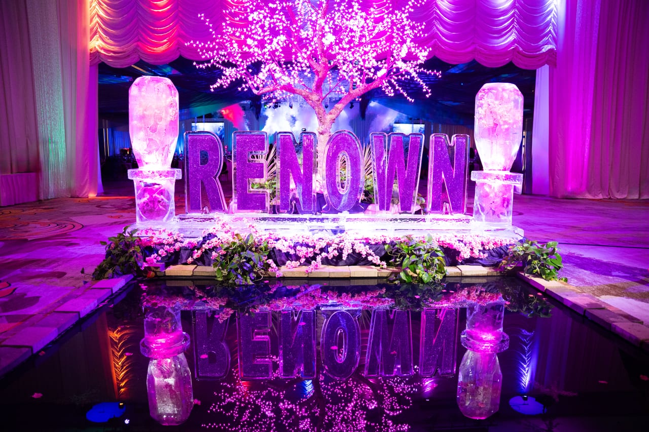 The RENOWN ice sculpture glowing purple and reflected in the pool below