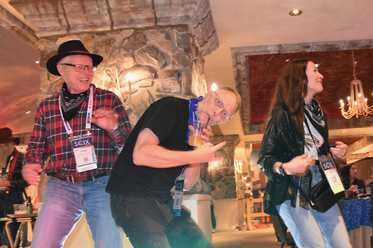 A SciX Gala guest in a cowboy hat and bandana dancing