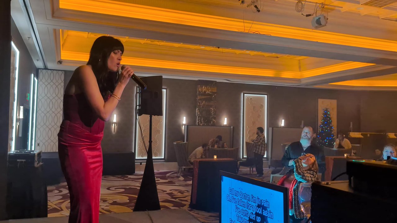 A guest singing karaoke in a red dress at the Sierra Air holiday party