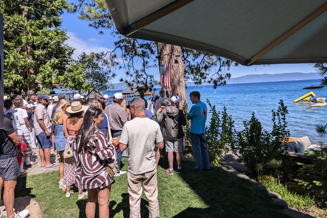 Fourth of July guests on a lakeside lawn watching Lake Tahoe under the pines