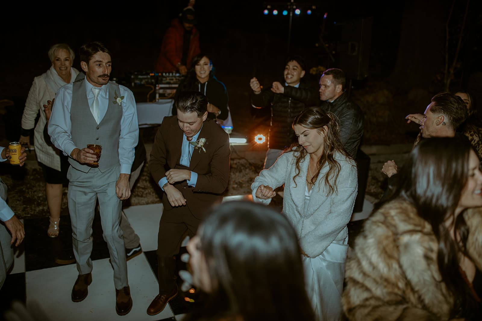Guests dancing on a checkered dance floor at a night wedding reception