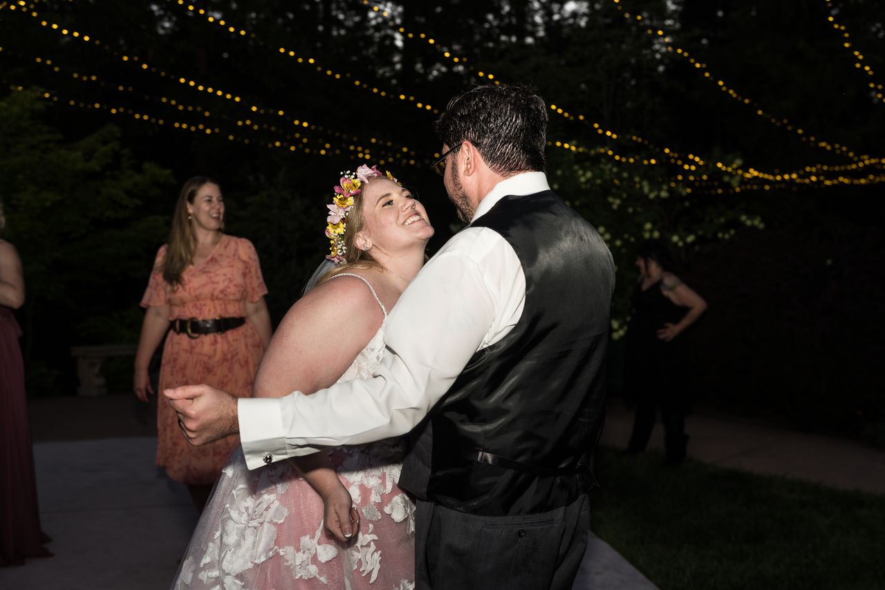Abney smiles up at Chris while they dance under string lights after dark