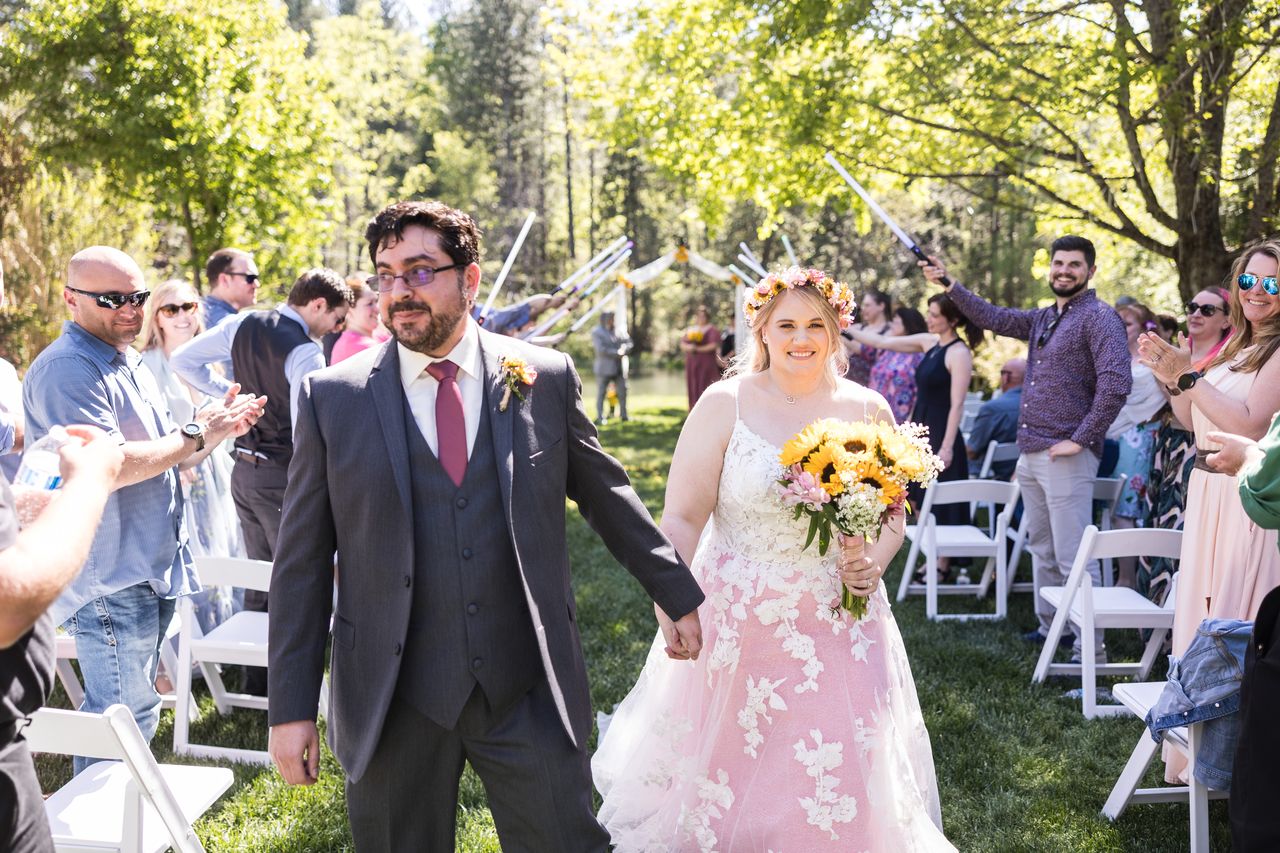 Abney looks toward the camera as she and Chris walk up the aisle under their guests' lightsabers