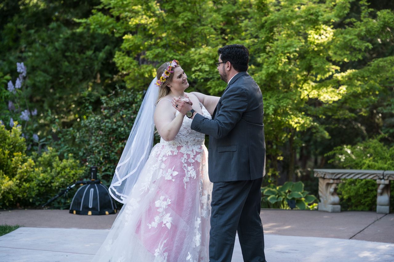Abney and Chris share their first dance on the patio, framed by green trees