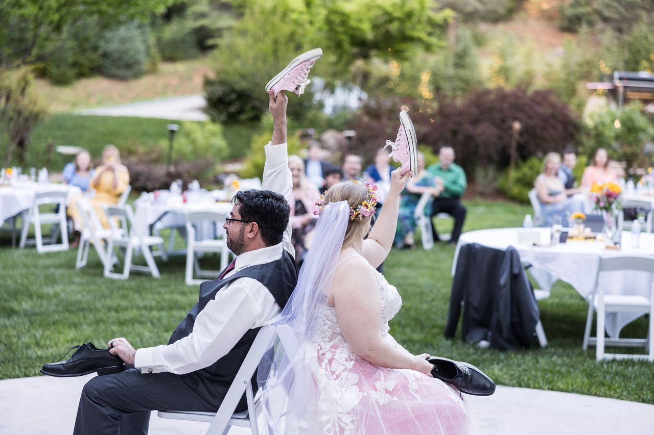 Abney and Chris hold up their shoes during the shoe game while their guests watch from the lawn