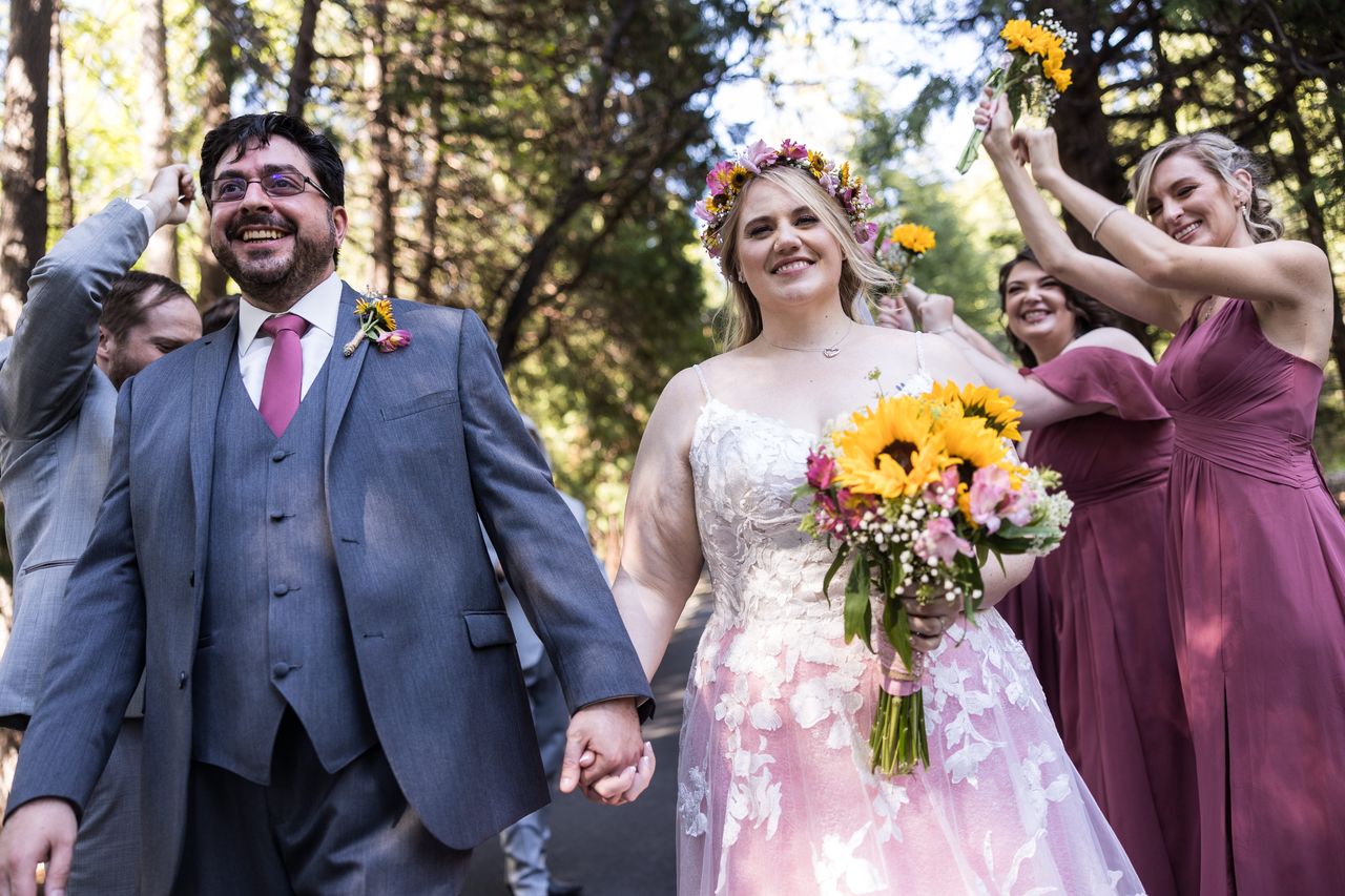 Abney smiles at the camera as she and Chris walk ahead of their cheering wedding party