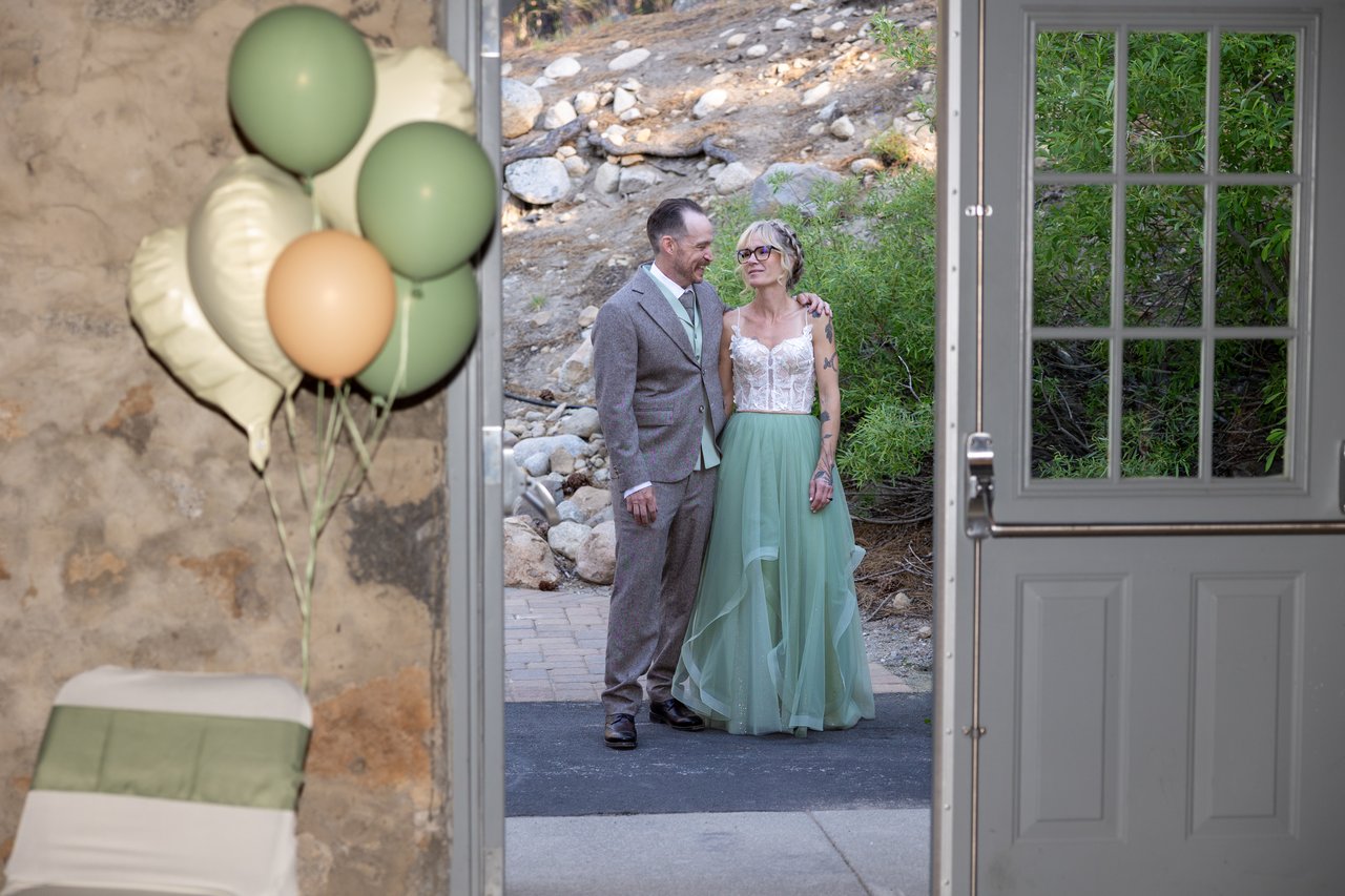 Amy and Justin wait at the hall door beside the balloons before their entrance
