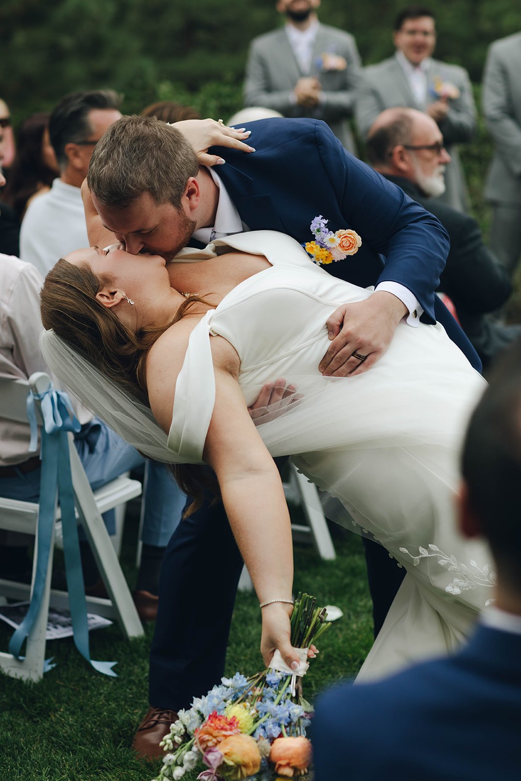 Peter dips Autumn for a kiss in the aisle while guests smile behind them