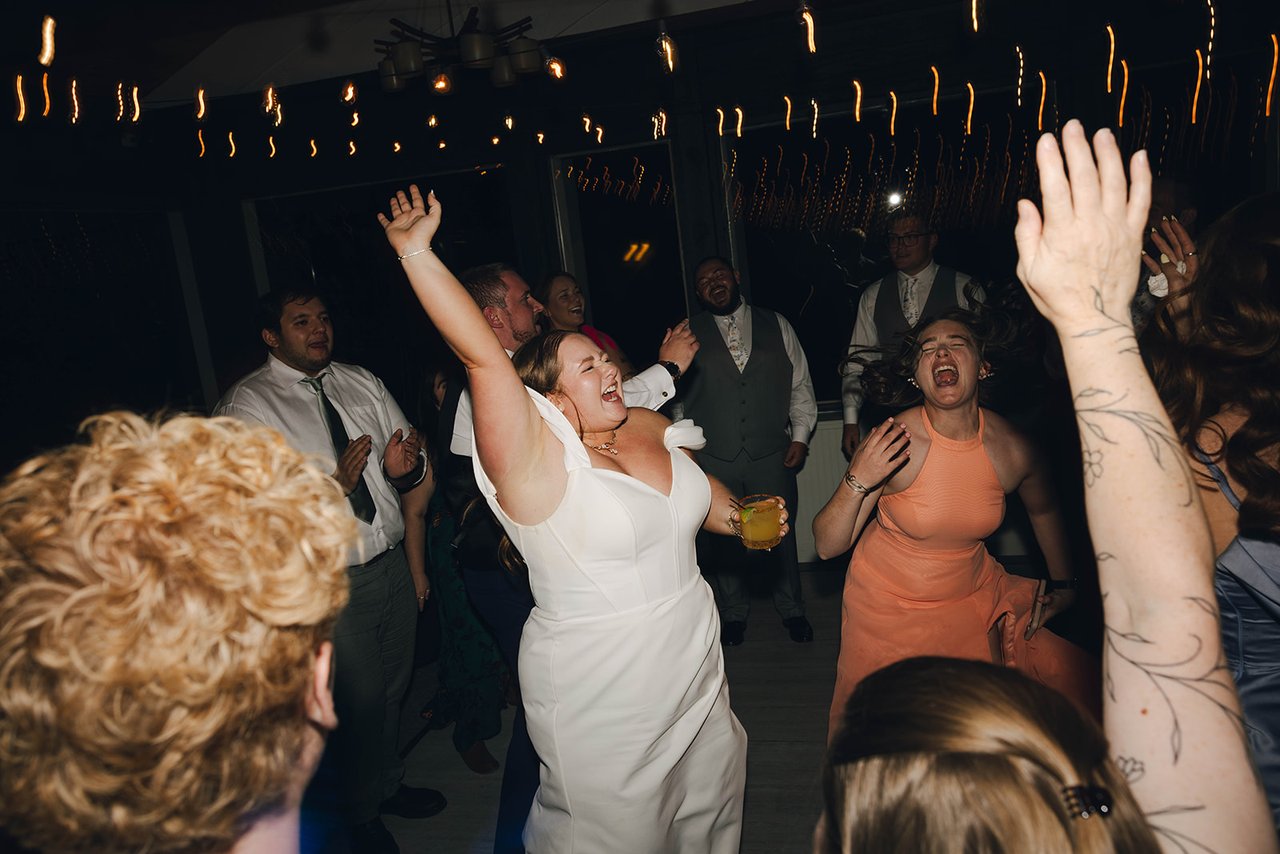 Autumn sings with her arm up on the dance floor, surrounded by guests
