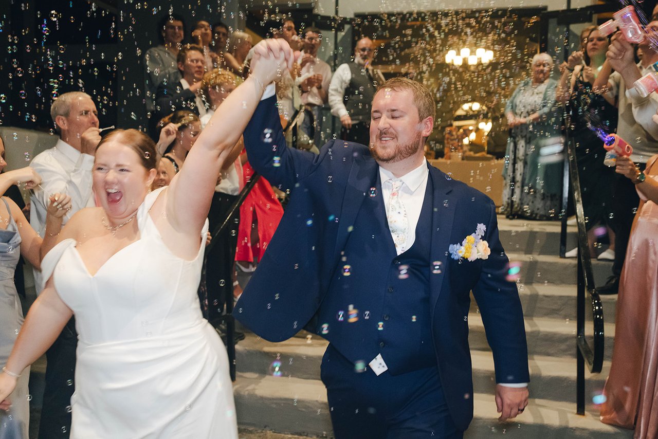 Autumn cheers with her hand joined to Peter's and raised high as guests fill the air with bubbles