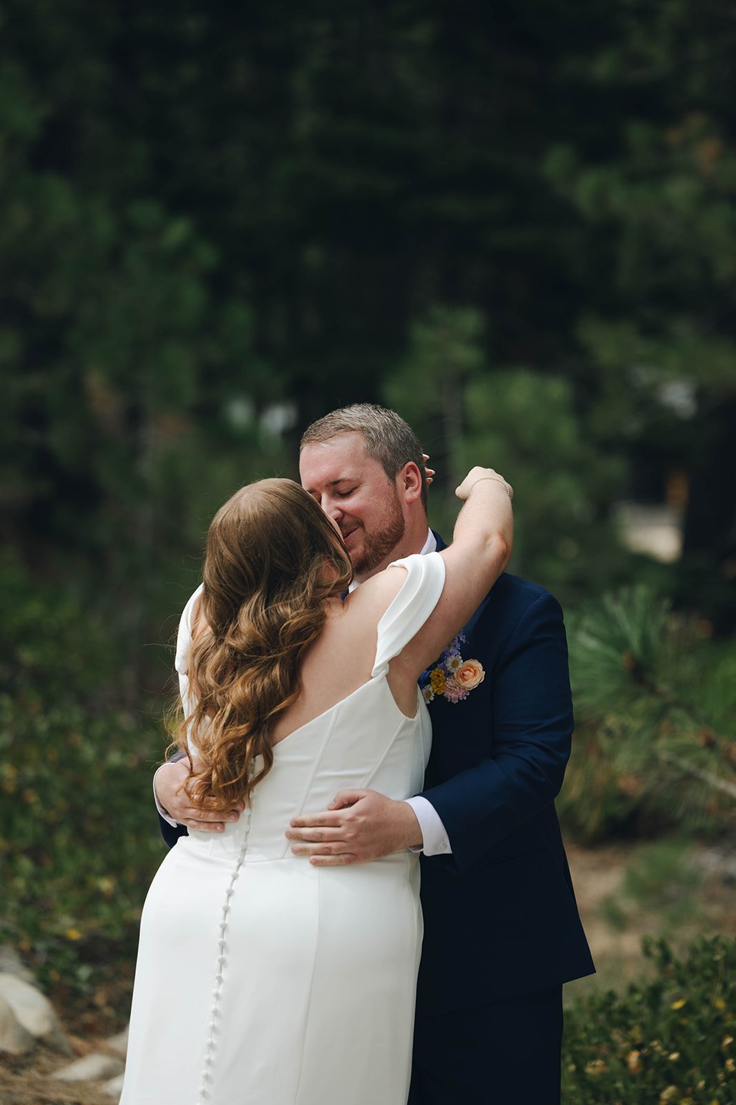 Peter smiles with his eyes closed as he hugs Autumn among the pines