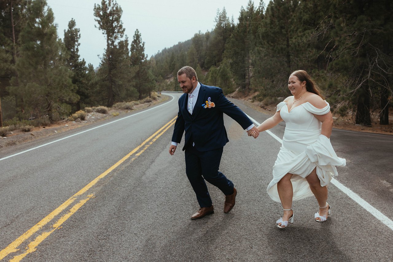 Autumn and Peter skip hand in hand down the middle of a mountain road