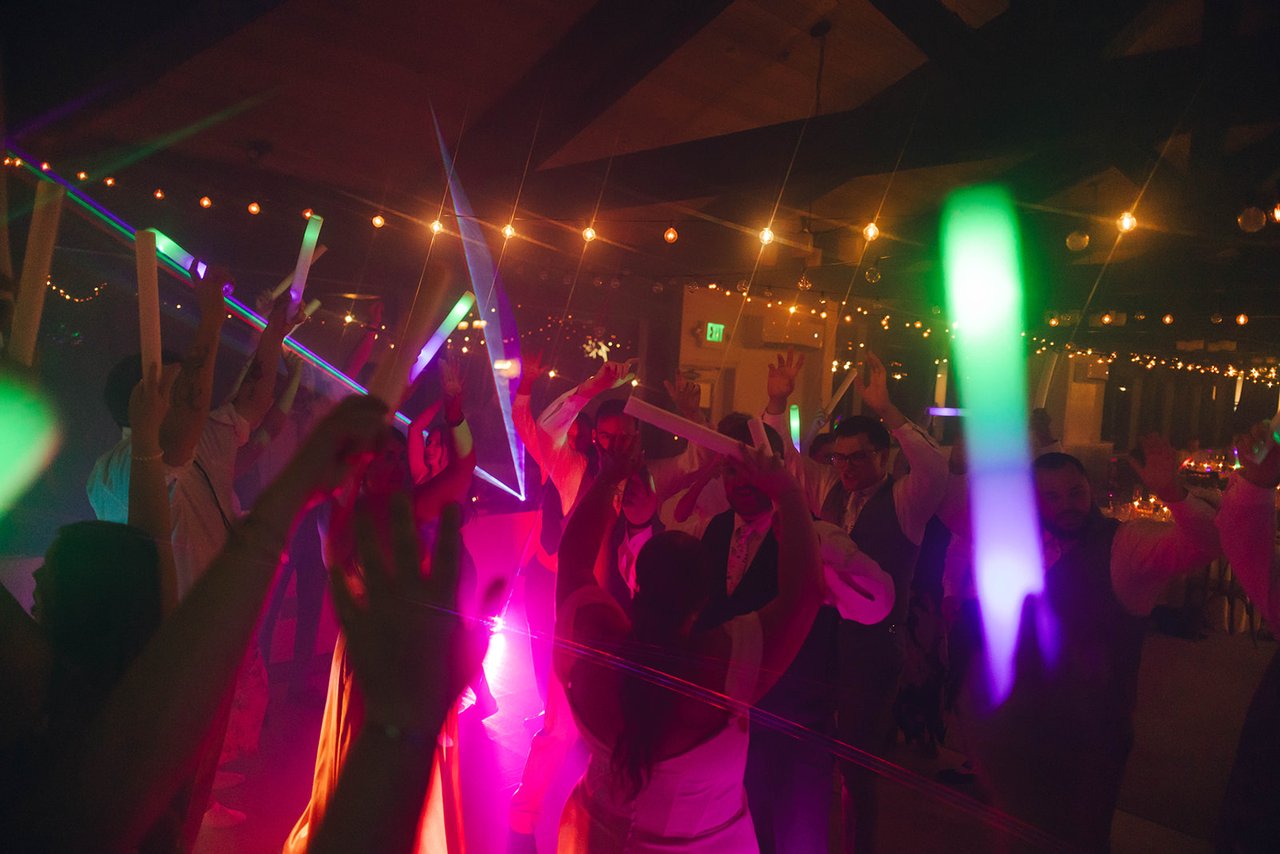 The dance floor in red and magenta light, with lasers and a green glow stick in front