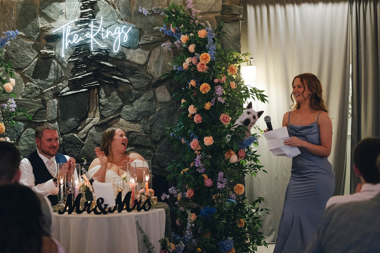 A toast read into the microphone while Autumn and Peter laugh at the sweetheart table