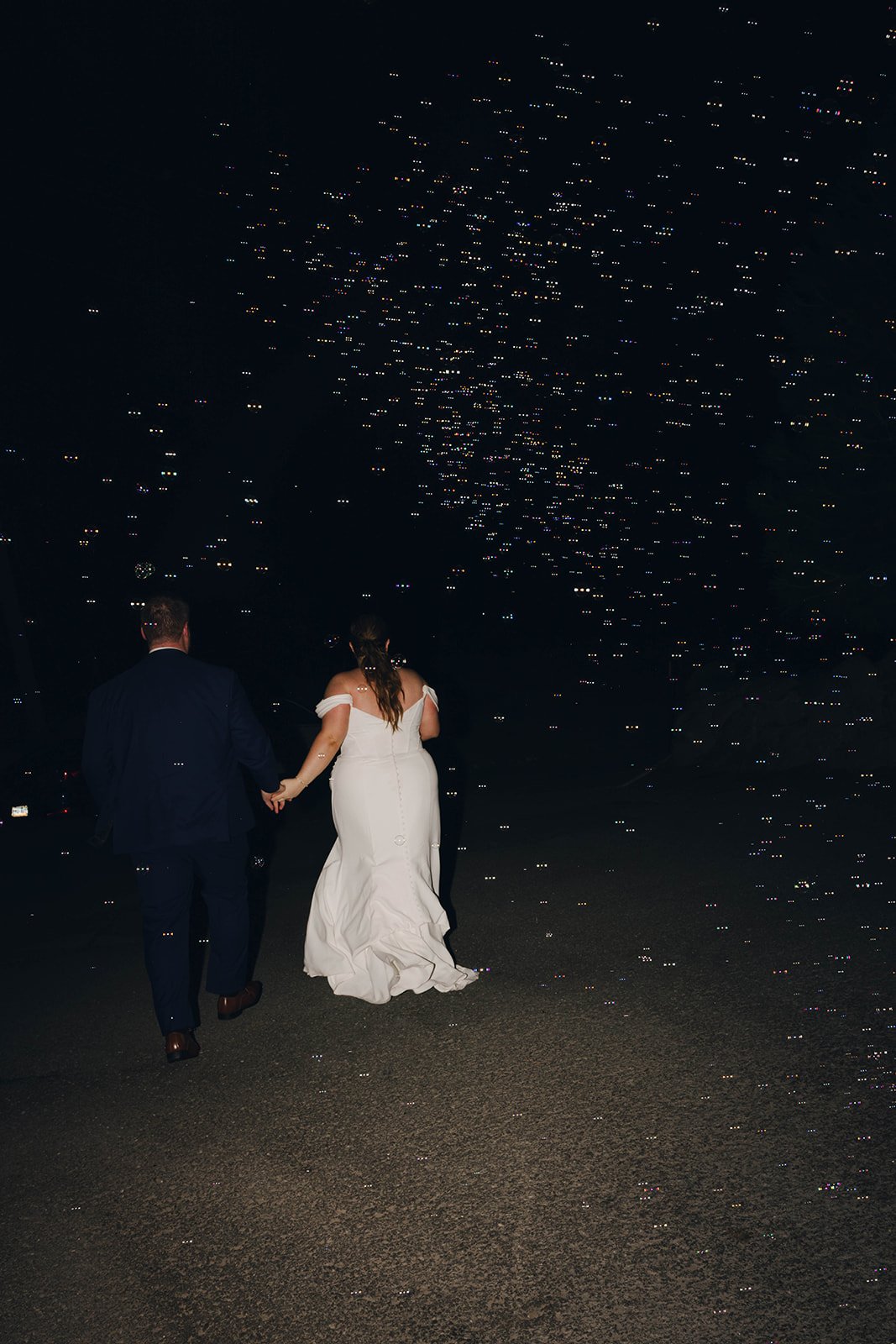 Autumn and Peter walk off hand in hand into the night with bubbles drifting overhead