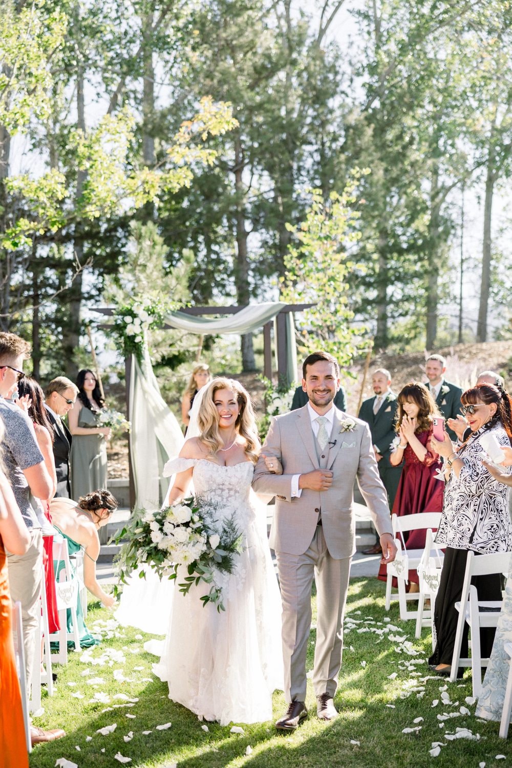 Britt and Chris laugh as they walk back up the aisle at The Club at Rancharrah