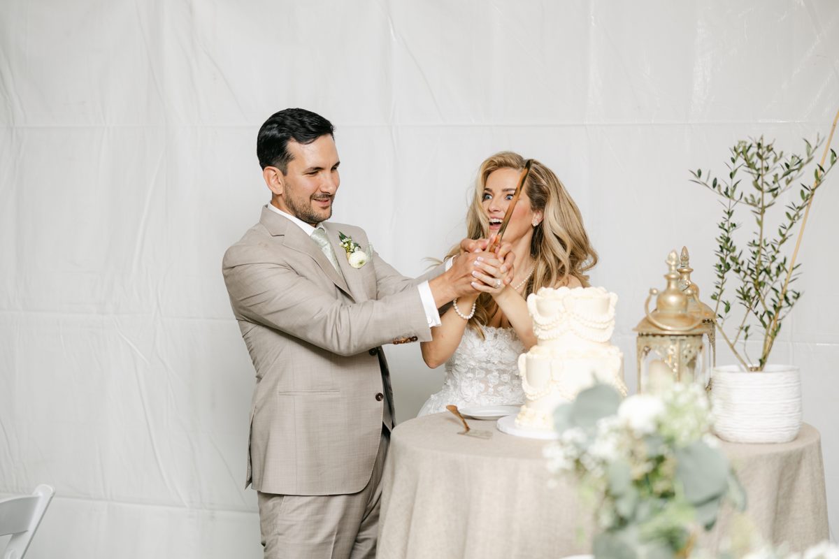 Britt and Chris laugh while cutting their wedding cake
