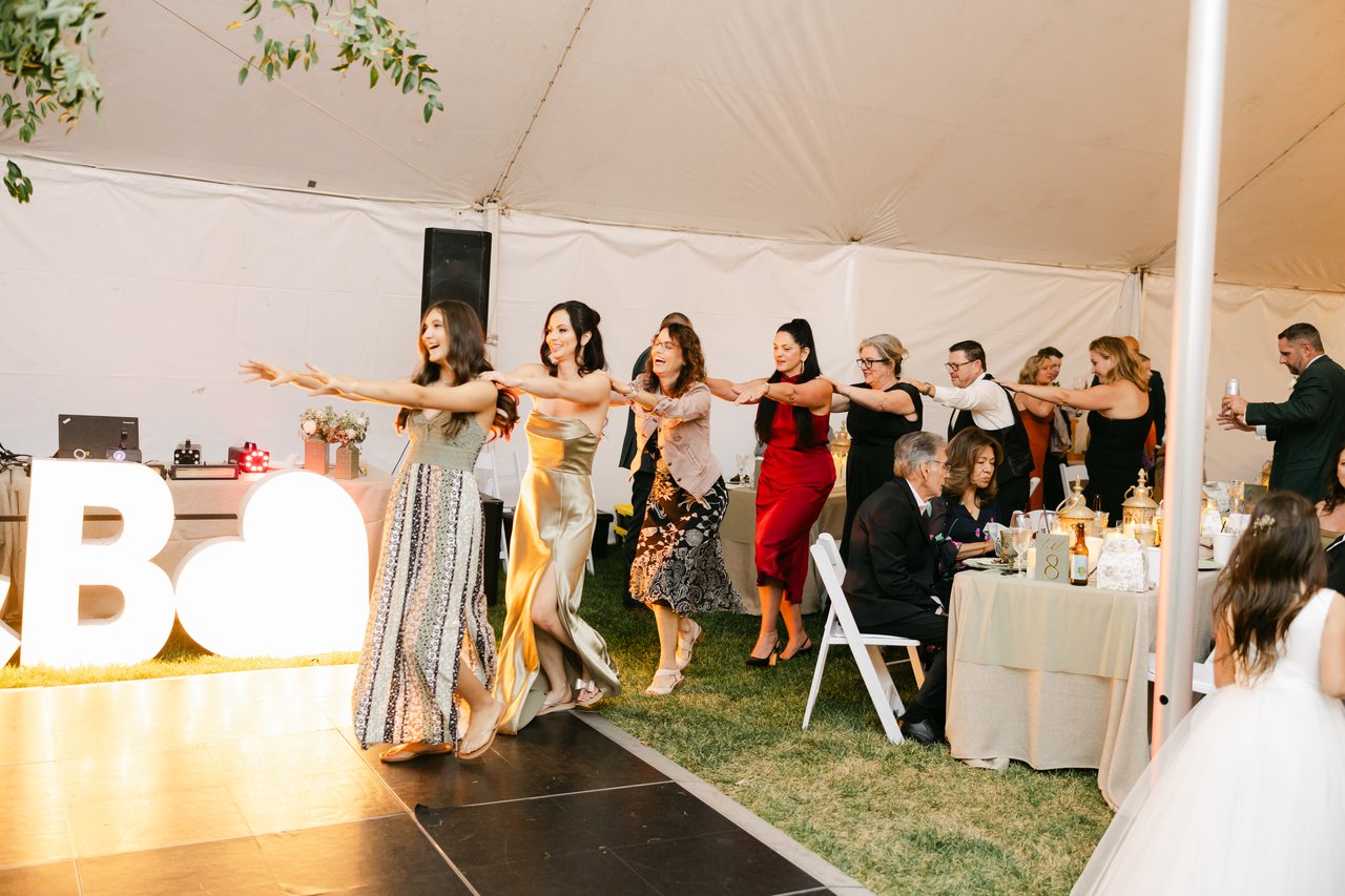 The conga line winds past the glowing letters as guests cheer from their tables