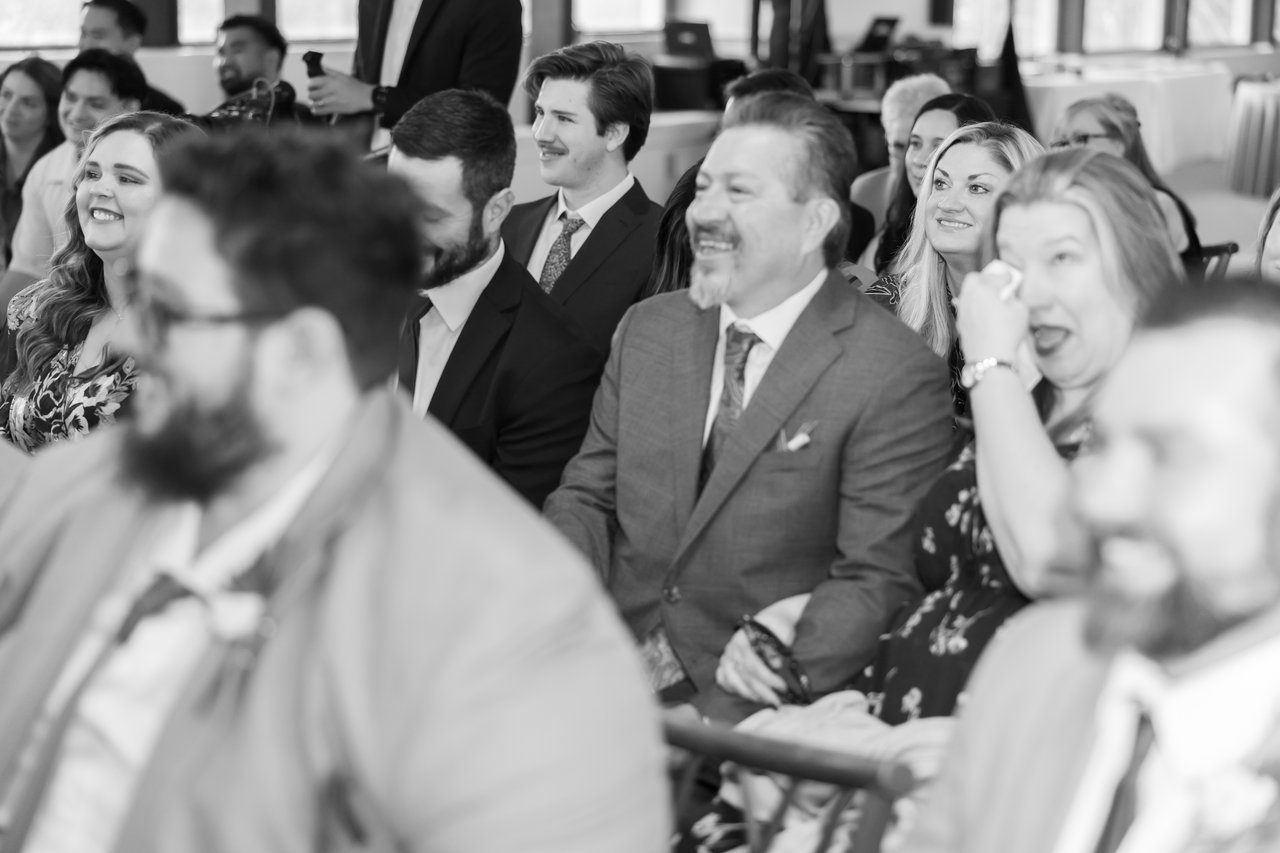 Guests laugh and wipe away tears during the ceremony, in black and white