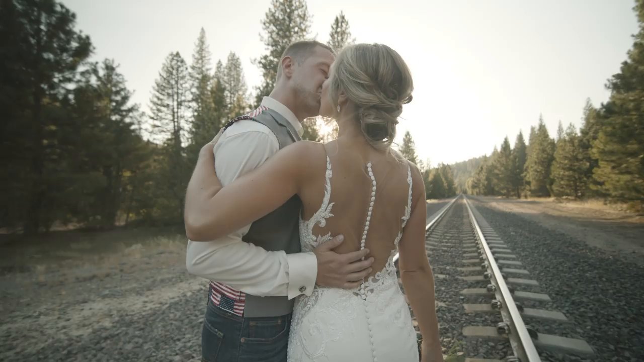 Danielle and Scott embrace beside the railroad tracks in the golden light