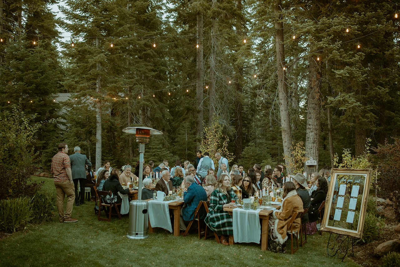 A wide view of dinner at long tables under the trees