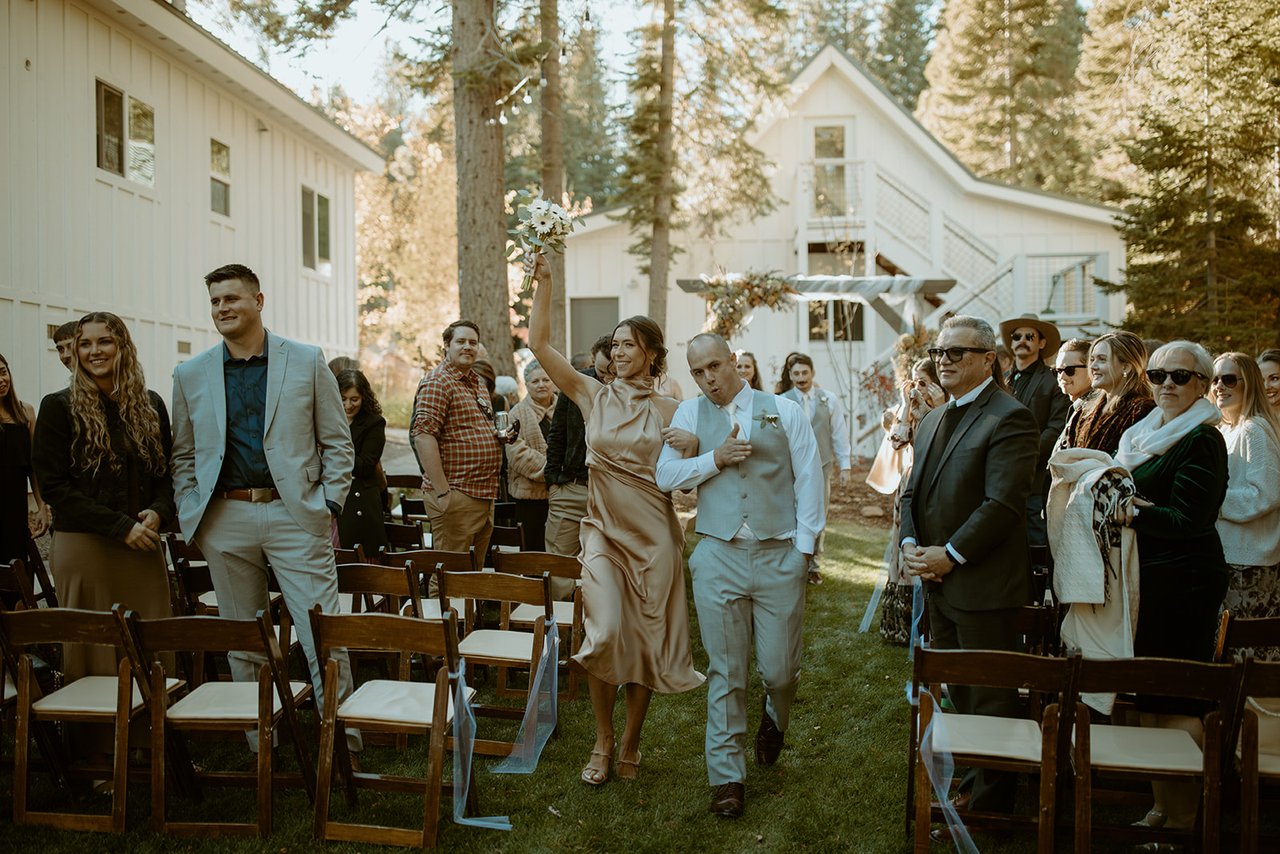 Guests cheer as the bridal party walks back up the aisle