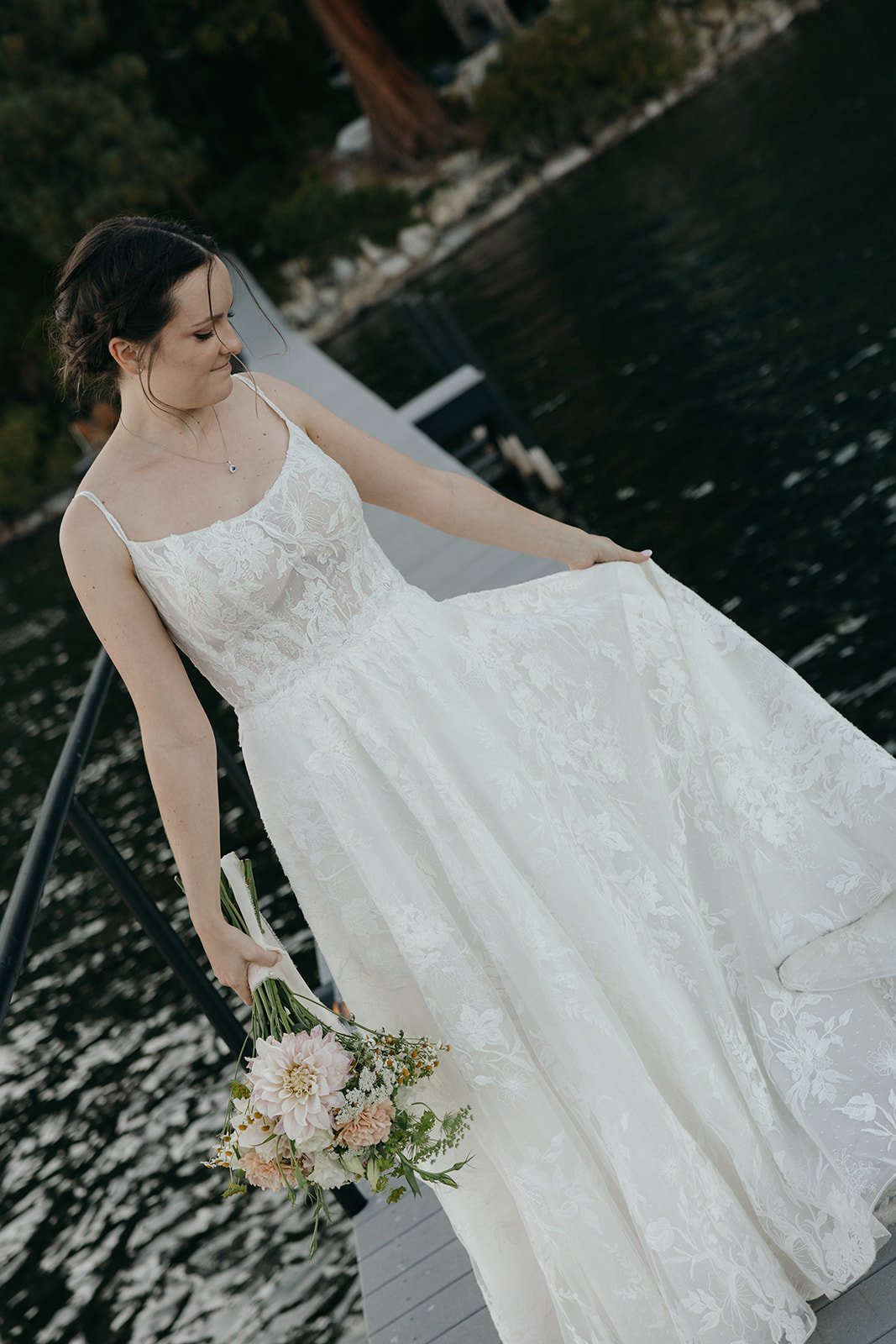 Emma looks down as she swirls her lace dress on the pier