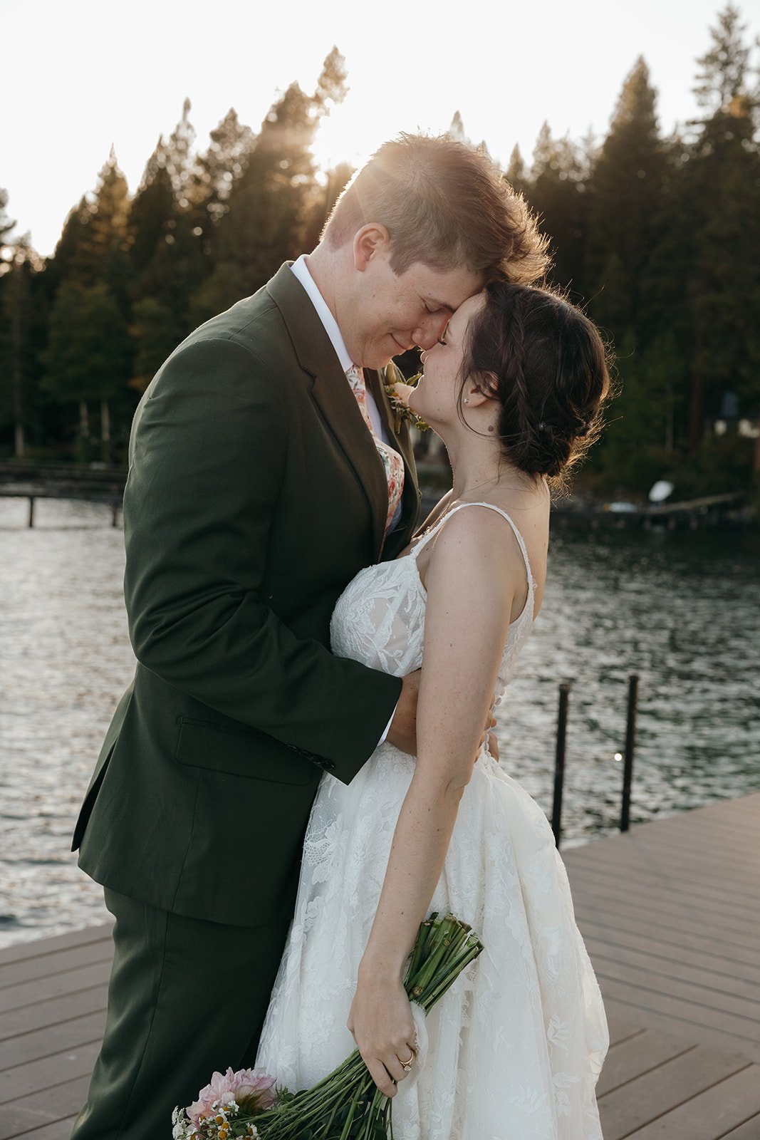 Emma and Jackson rest forehead to forehead with the sun setting behind the pines