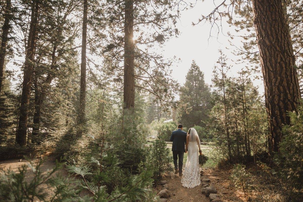Hannah and Kyle walk away down a forest path among the pines