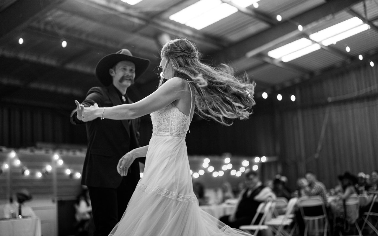 Kerstyn twirls on the barn dance floor under the string lights, in black and white