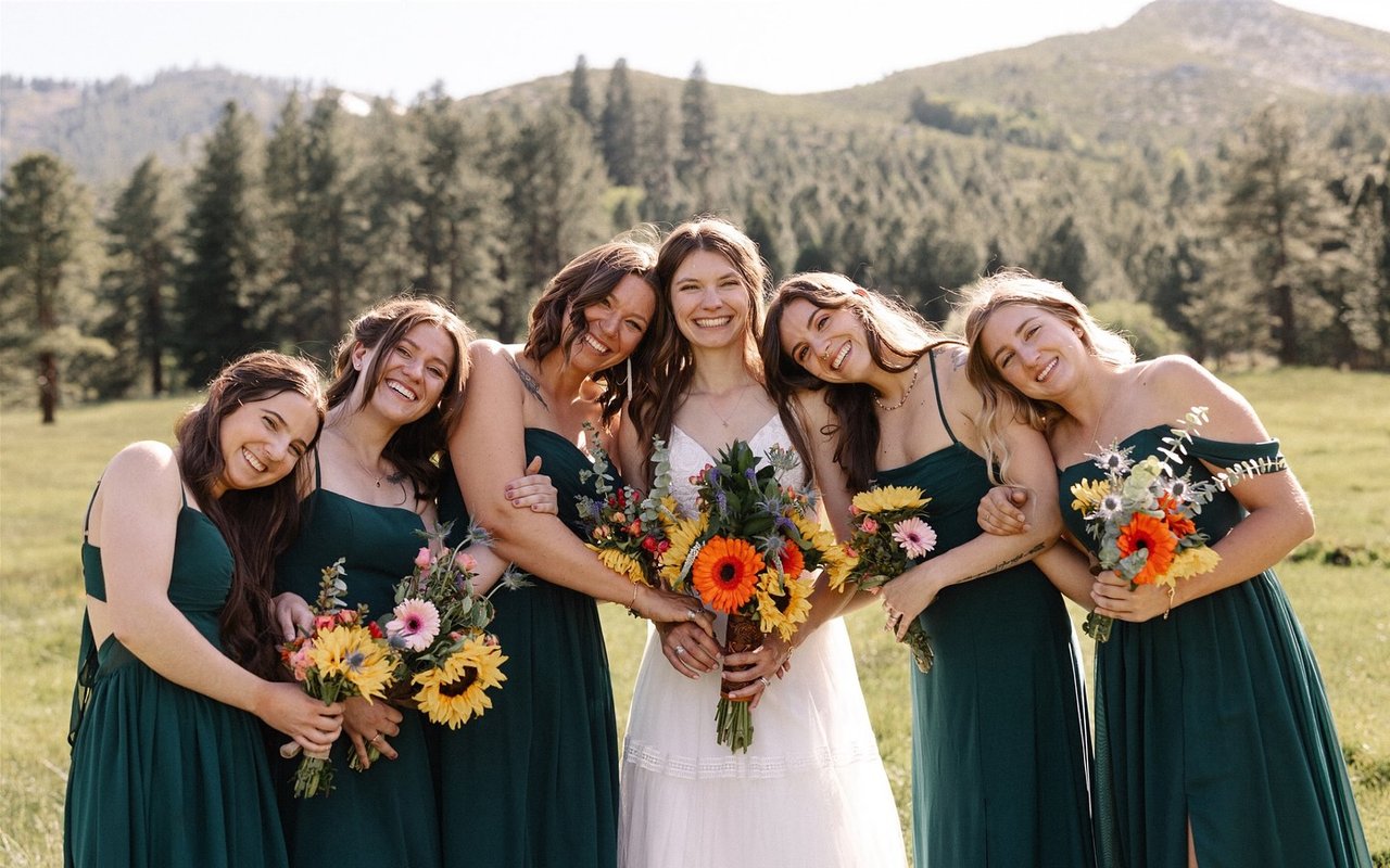 Kerstyn laughs with her bridesmaids in green dresses, all holding sunflower bouquets