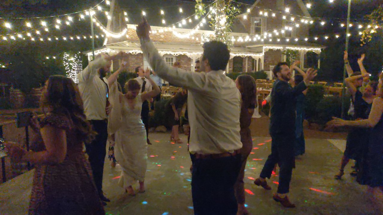 Lauren and her guests throw their hands up on the dance floor under the string lights