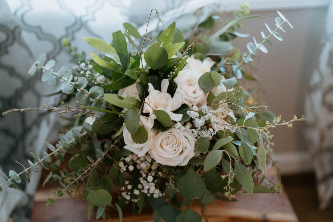 Montse's bouquet of white roses and eucalyptus resting on a wooden table