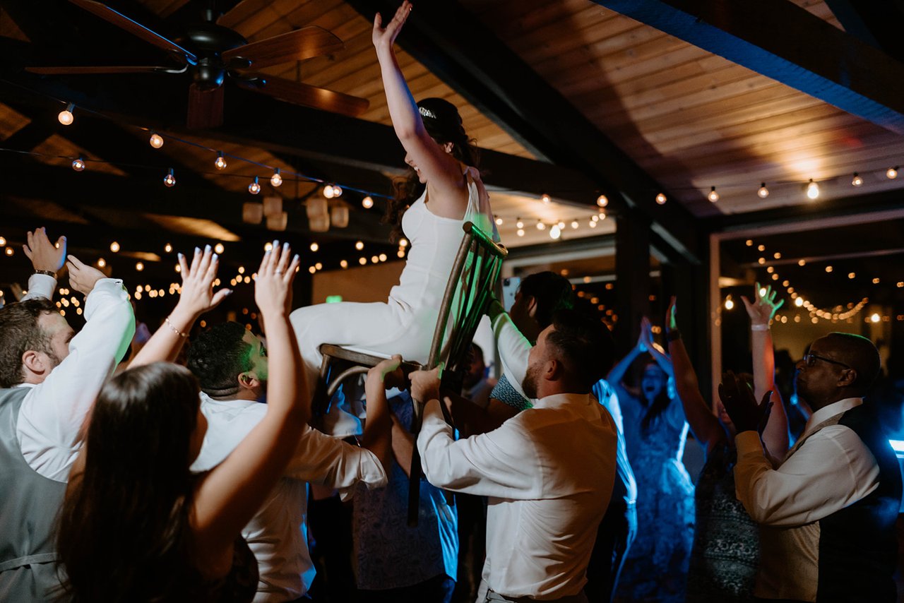 Guests lift Montse up in a chair over the dance floor