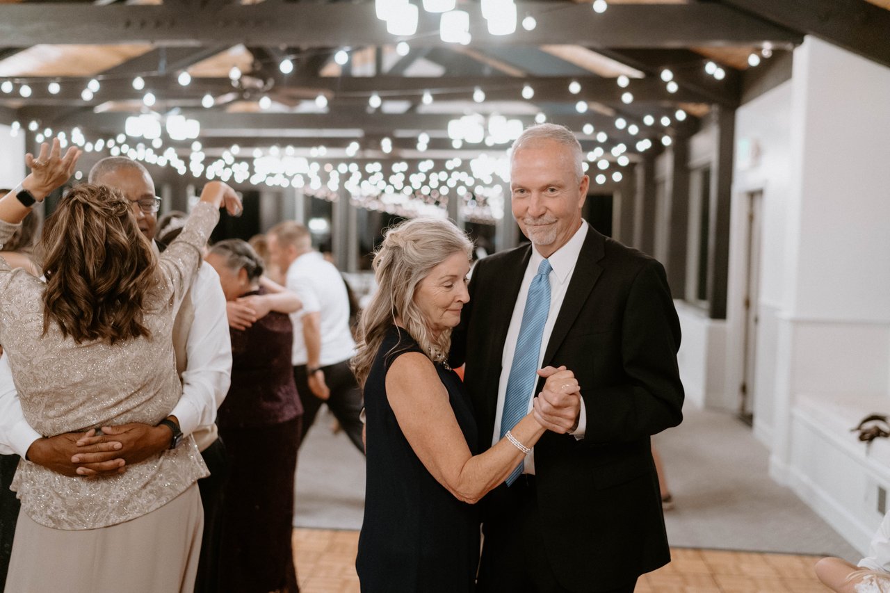 Guest couples slow dance under the string lights