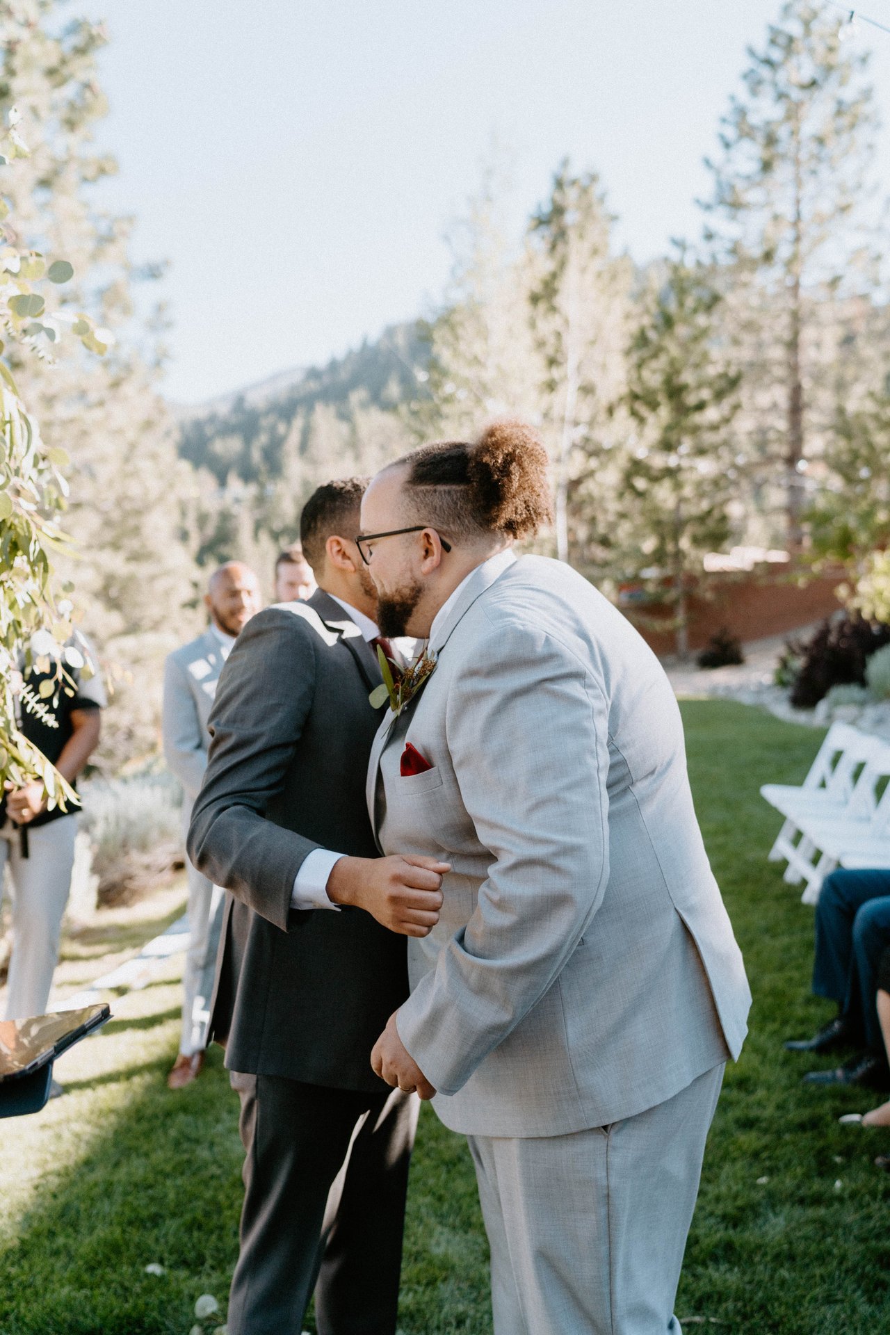 Jason greets a groomsman with a hug at the front of the aisle