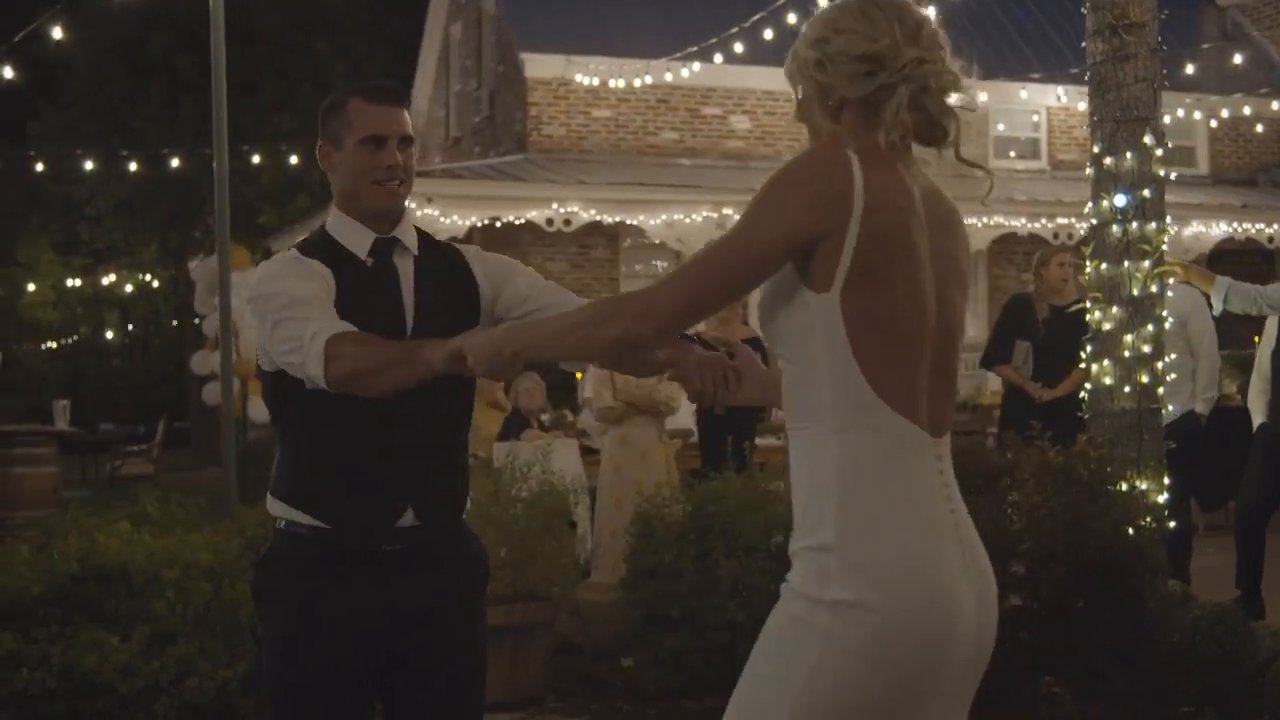 Nicole and Tim dance in front of the lit porch