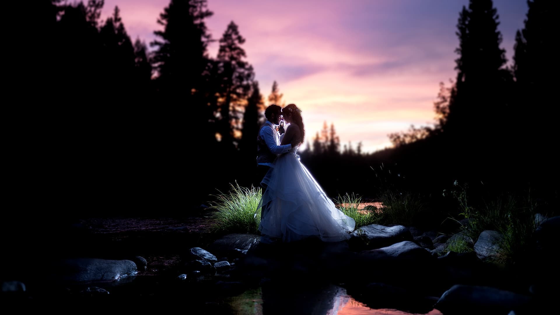 Shannon and Ryan embrace beside the river at dusk near Twenty Mile House